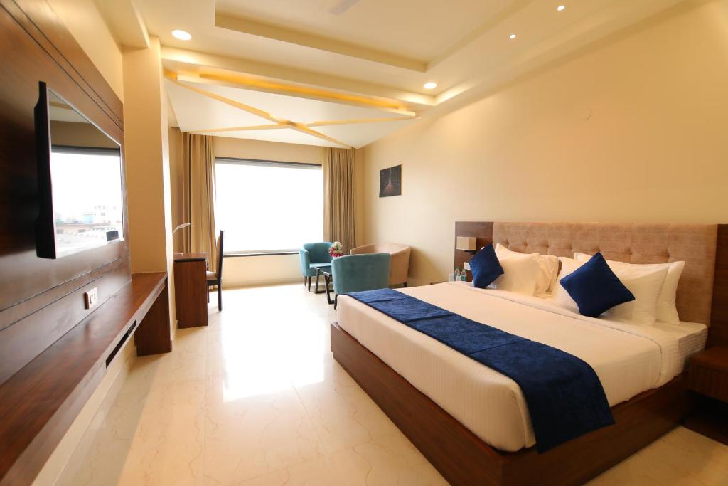 um quarto de hotel com uma cama e uma televisão de ecrã plano em The Forest Hill Hotel em Haridwar