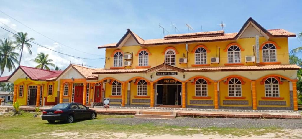 a yellow house with a car parked in front of it at RAZ HOTEL PANTAI PERANGINAN KELULUT in Marang