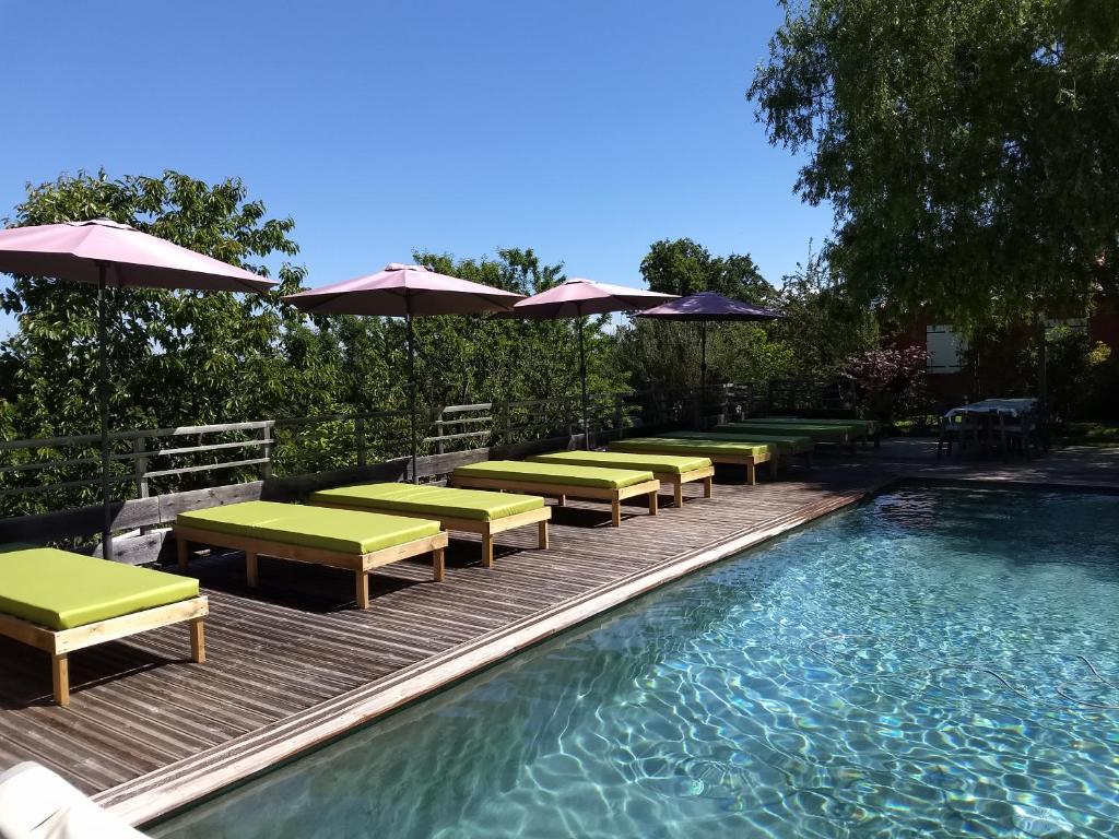 einen Pool mit Liegestühlen und Sonnenschirmen auf einer Holzterrasse in der Unterkunft Les Terrasses de Valensole in Valensole