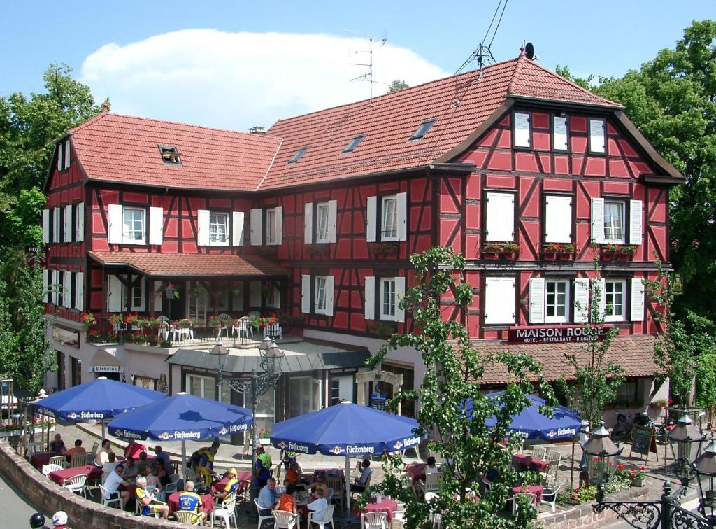 a building with tables and blue umbrellas in front of it at A la Maison Rouge Hôtel & Restaurant in Barr