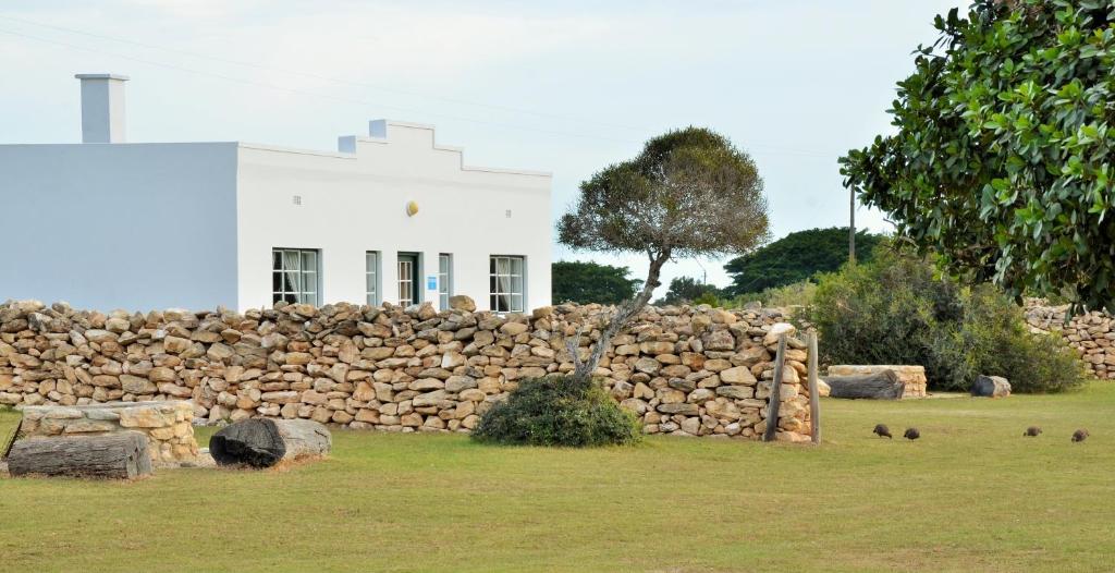 a stone wall in front of a white building at De Hoop Collection - Equipped Cottages in De Hoop Nature Reserve