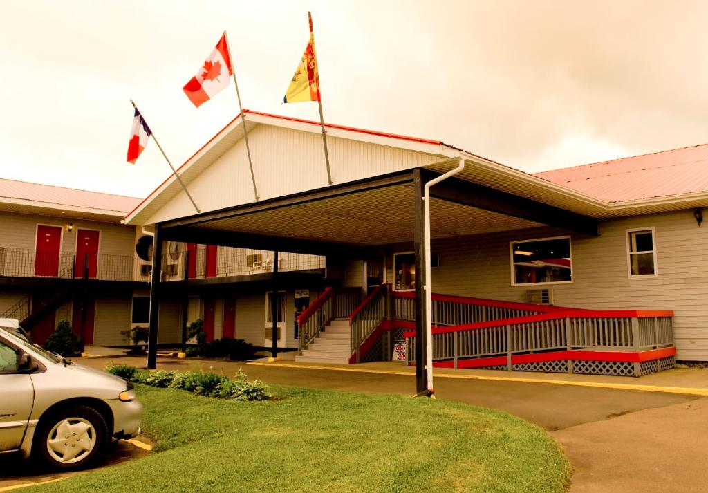 un'auto parcheggiata di fronte a un edificio con bandiere di Seely's Motel a Shediac