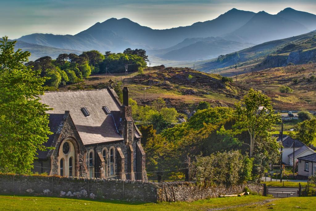 an old church on a hill with mountains in the background at Mountain Church in Capel Curig