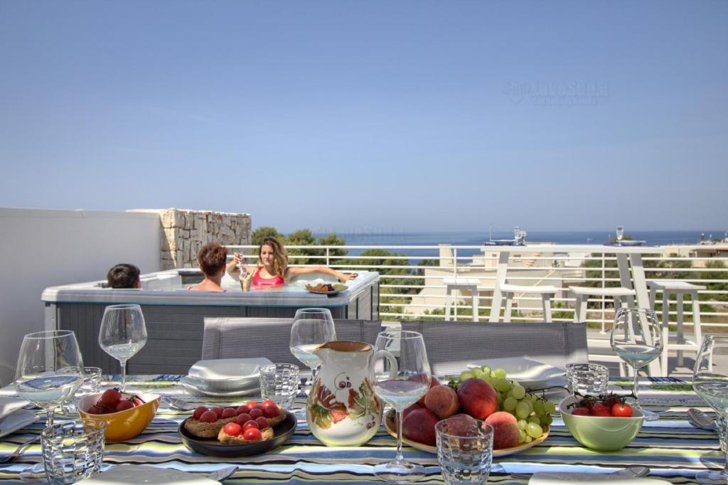 a table with plates of food and wine glasses at Jacuzzi Holiday Homes in Leuca