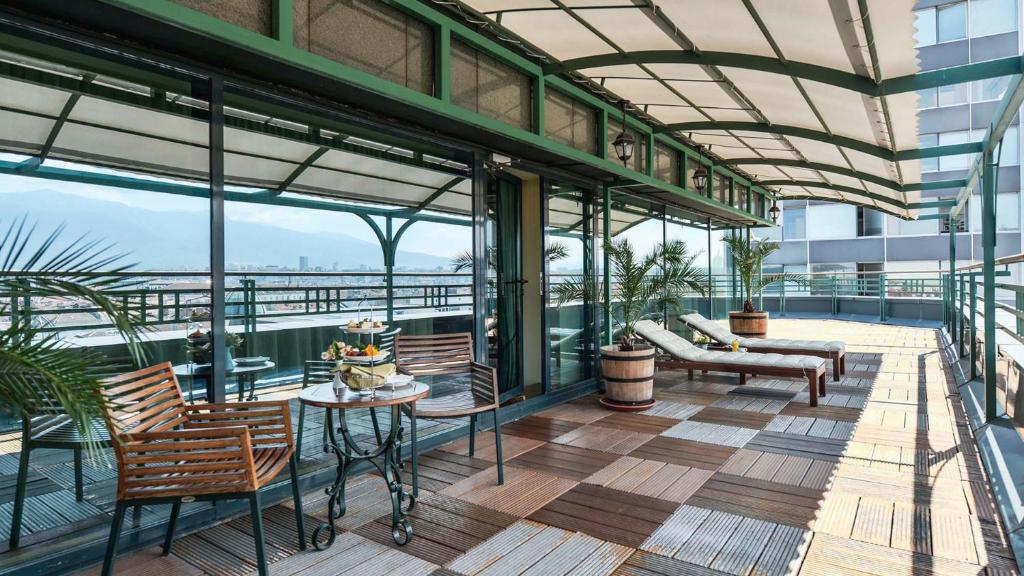 a balcony with chairs and tables on a building at Grand Hotel Sofia - Top Location, The Most Spacious Rooms in the City, Secured Underground Parking in Sofia