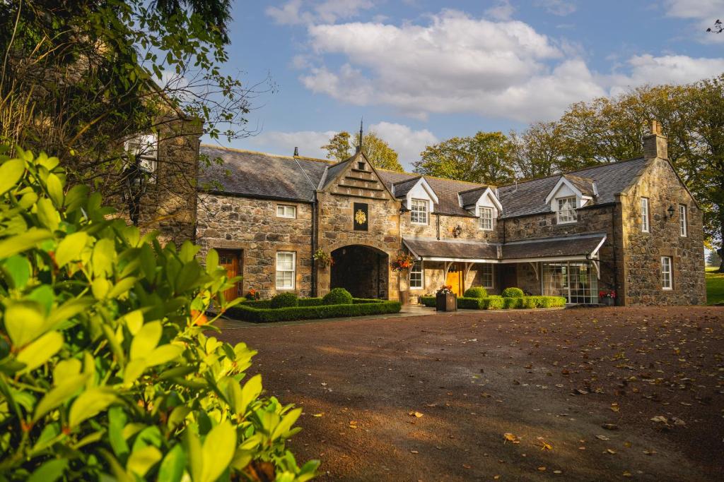 uma grande casa de pedra com uma grande entrada em Trump MacLeod House & Lodge, Scotland em Balmedie
