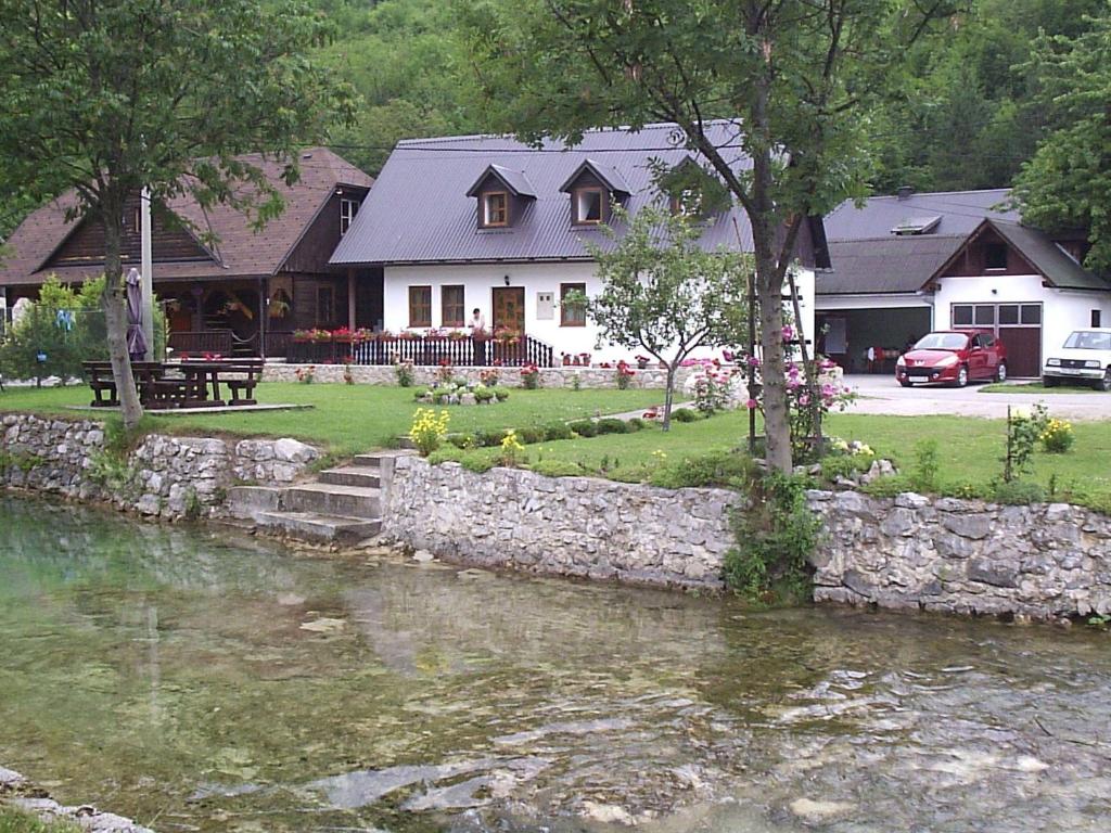 a house with a stone wall next to a river at Apartment Mira in Korana