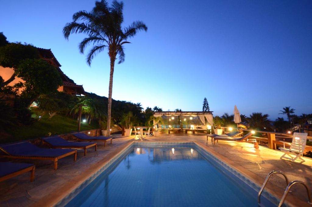 una piscina con tumbonas y una palmera en Aguabúzios Hotel, en Búzios