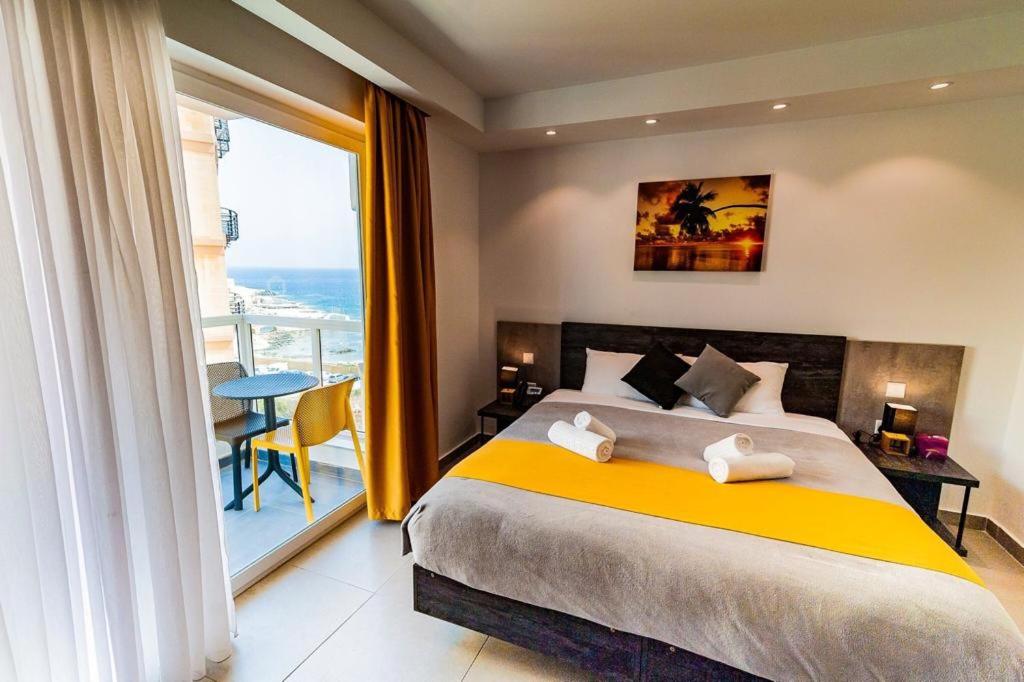 a bedroom with a large bed and a balcony at Hotel Shoreline in St. Julianʼs