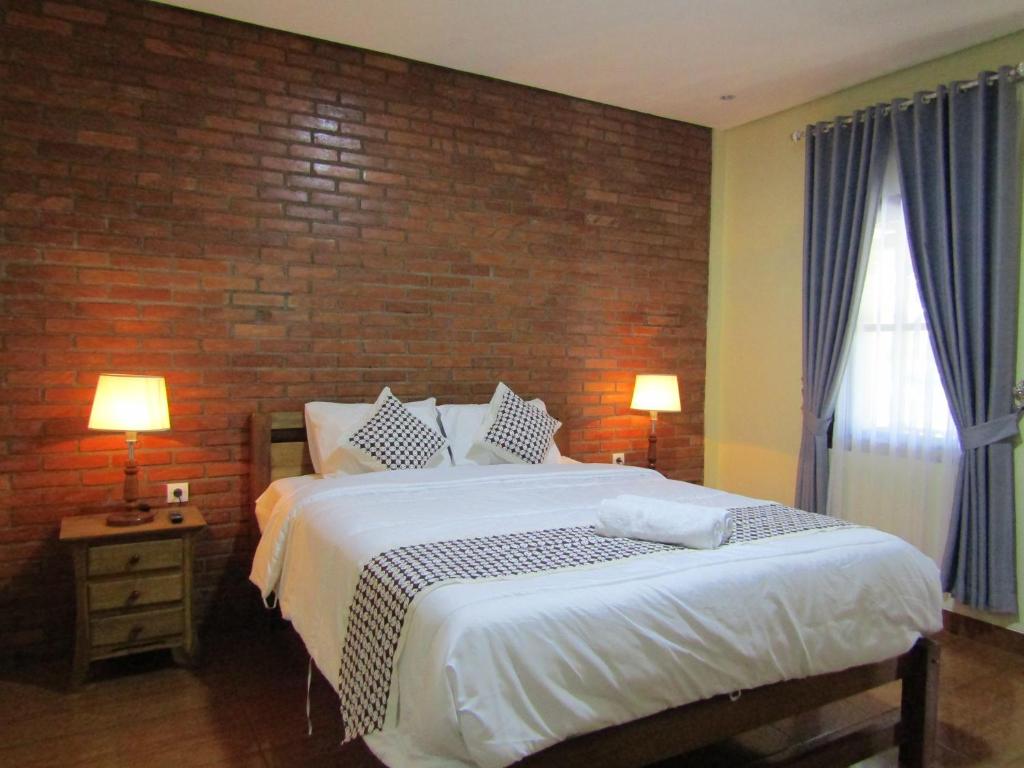 1 dormitorio con 1 cama grande y pared de ladrillo en Nia Maretta House Syariah, en Magelang