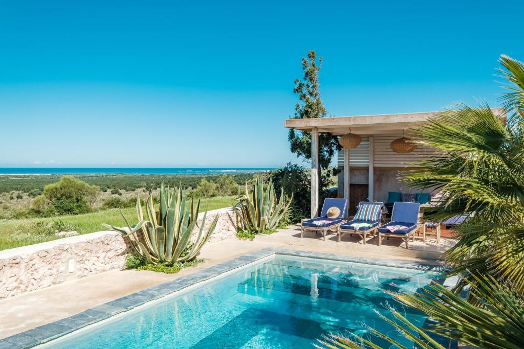 - une piscine avec 2 chaises et une maison dans l'établissement Riad Tamayourt Ocean View & piscine chauffée à 30, à Essaouira