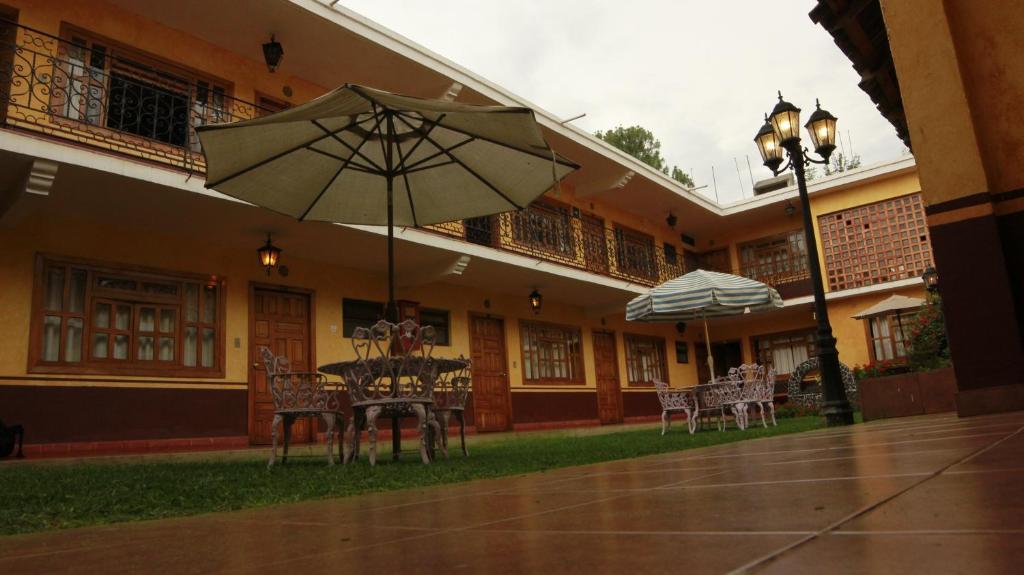 une table et des chaises avec un parasol en face d'un bâtiment dans l'établissement Posada de la Salud, à Pátzcuaro