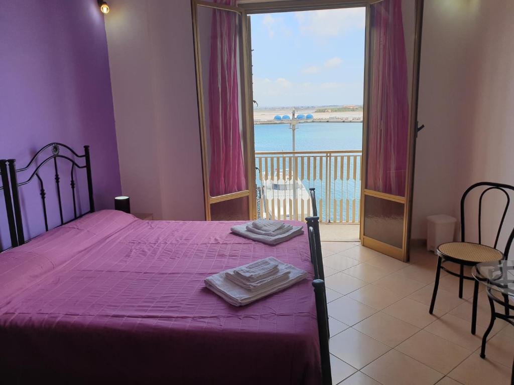 una camera da letto con un letto con lenzuola viola e una finestra di Beb al porto da joseph a Trapani