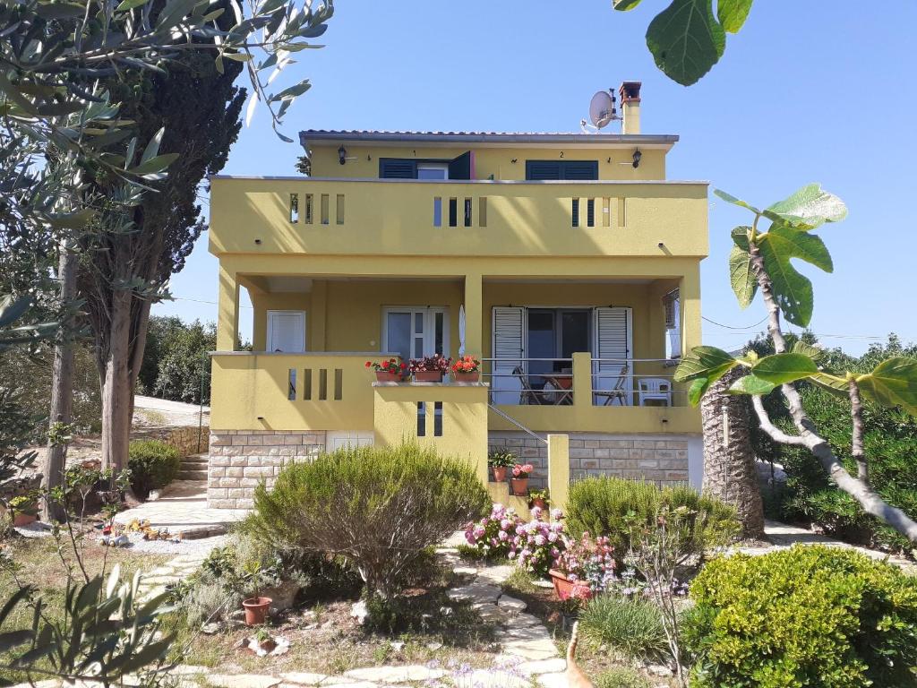 a yellow house with plants in front of it at Apartment Branko in Sutomišćica