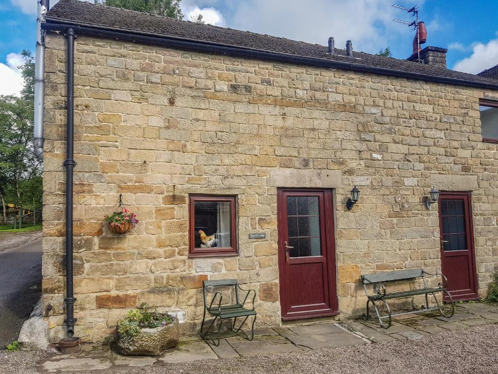 a brick building with a dog sitting in a window at Rambler's Cottage in Tansley