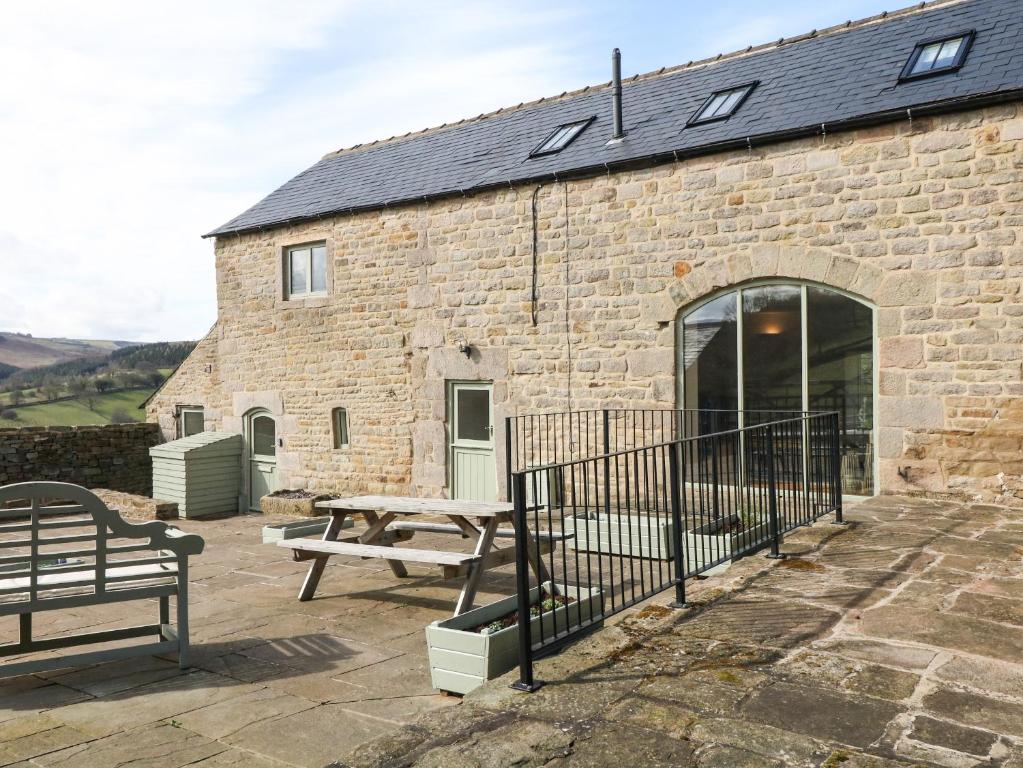 a brick building with a picnic table and a bench at Broadwood Barn in Hathersage
