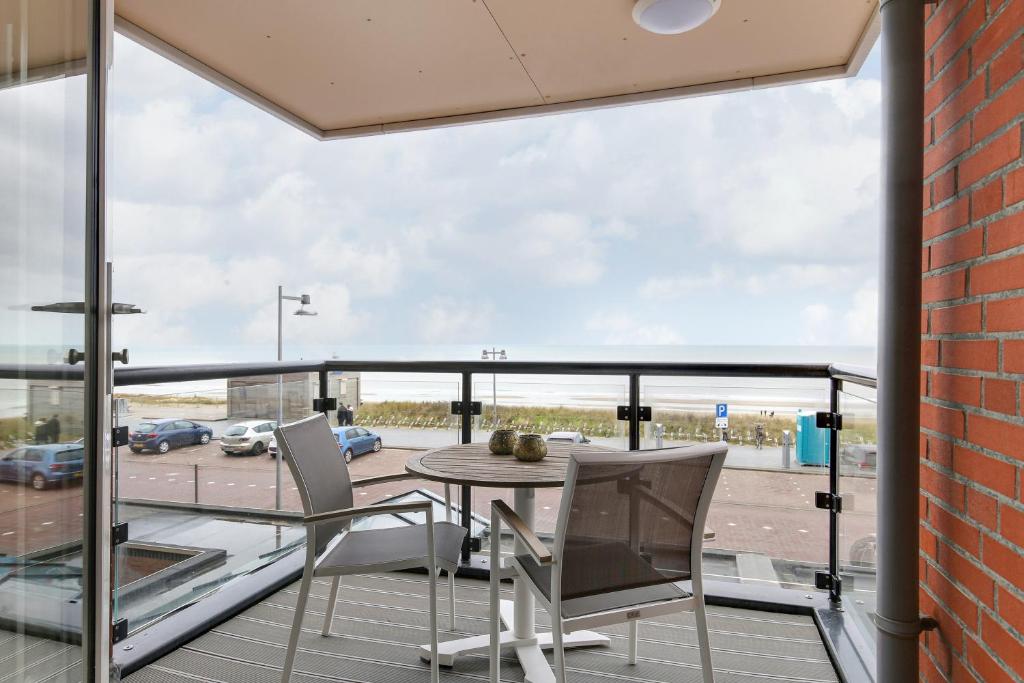 a balcony with a table and chairs looking out onto a parking lot at DE TRINTEL met zeezicht in Egmond aan Zee