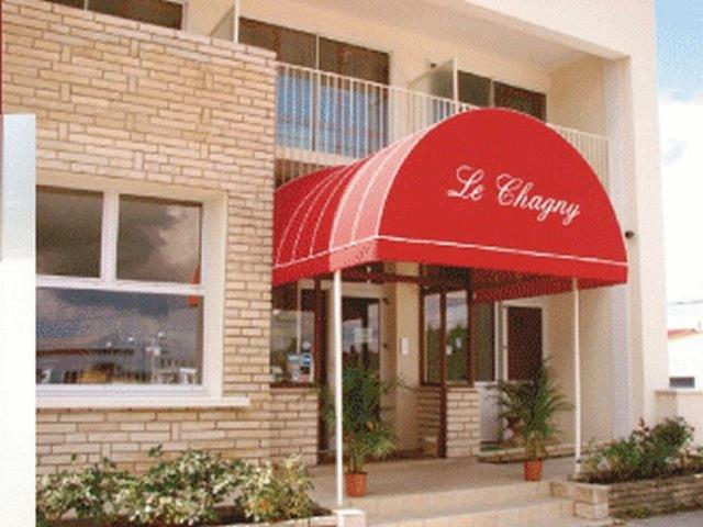 un restaurant avec un parasol rouge en face d&#39;un bâtiment dans l&#39;établissement Le Chagny, à Chagny