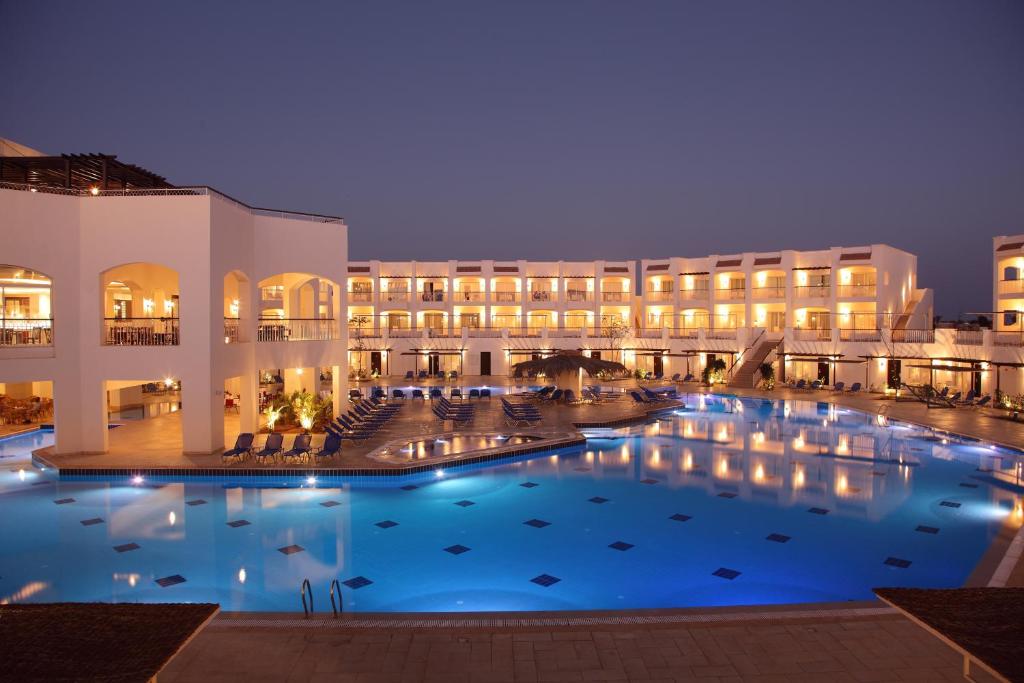 a large pool in front of a hotel at night at Jaz Sharks Bay in Sharm El Sheikh