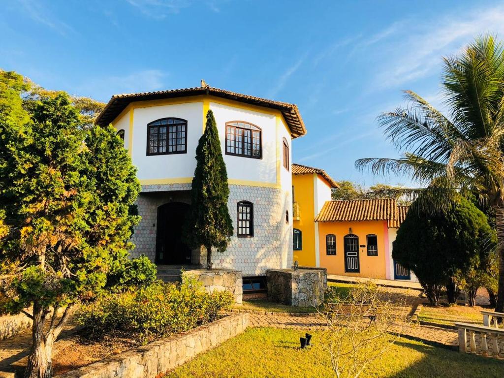 a yellow and white house with a palm tree at Pousada Morada Do Sol mg in São João del Rei