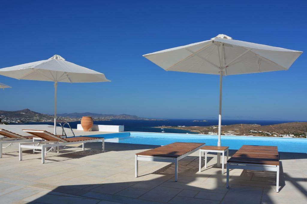 basen z 2 parasolami i krzesłami oraz basen w obiekcie White Blue Houses & Apartments Paros w mieście Parikia