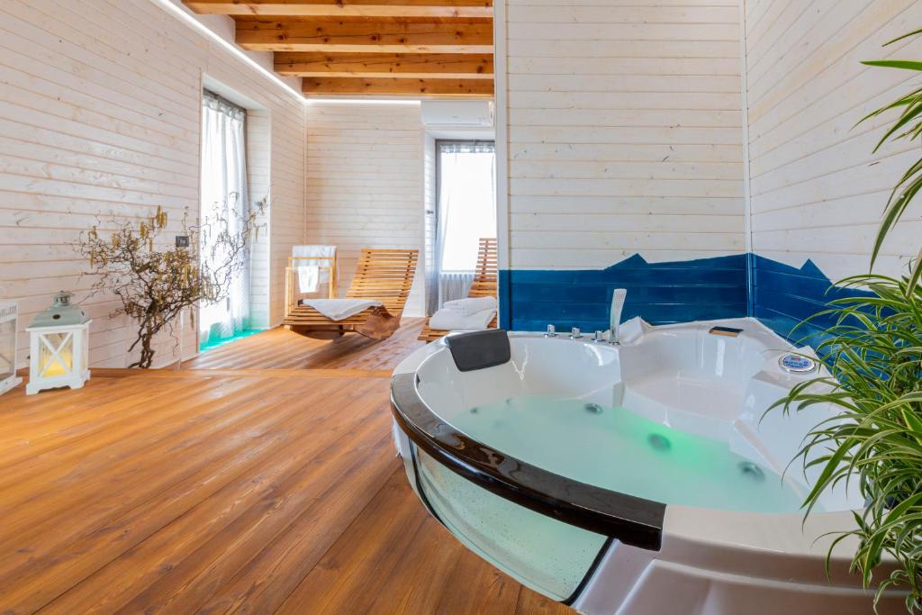 Habitación con suelo de madera y baño con bañera. en La Perla di Costozza - Exclusive Wellness & Spa, en Longare