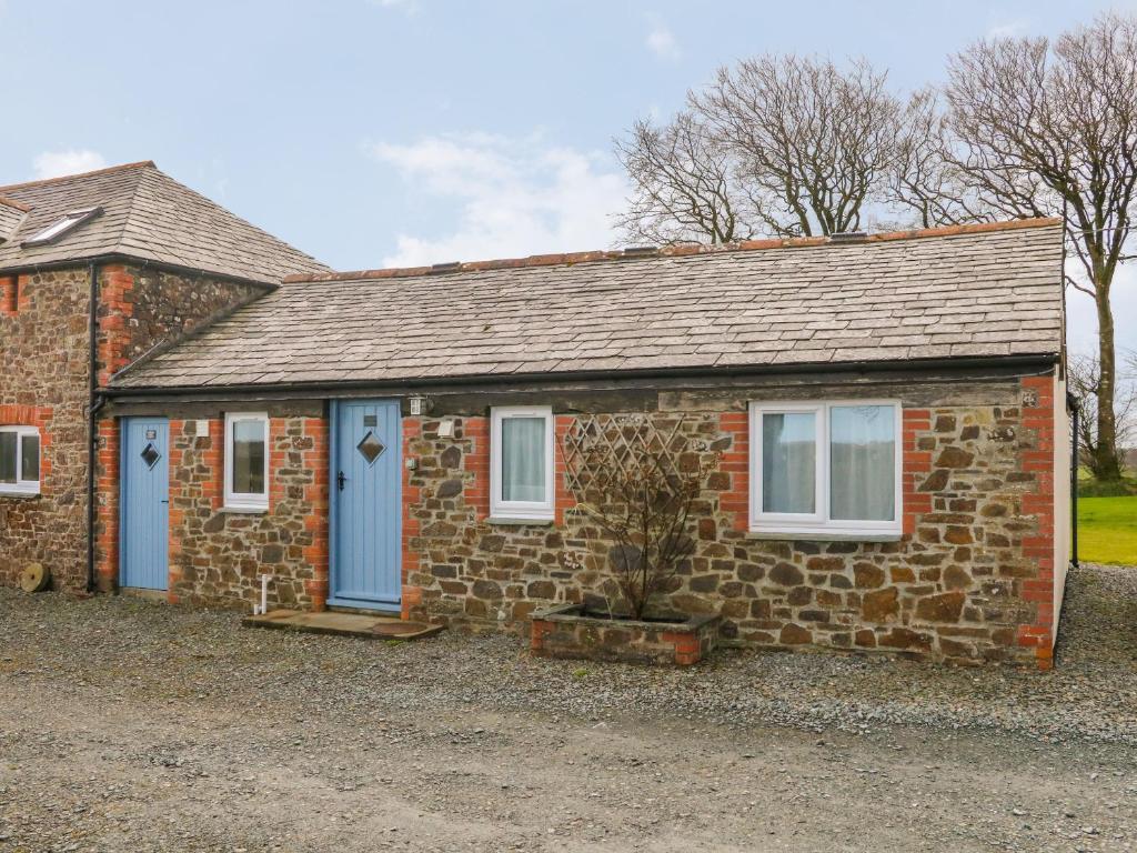 a small brick house with blue doors and windows at The Cottage in Holsworthy