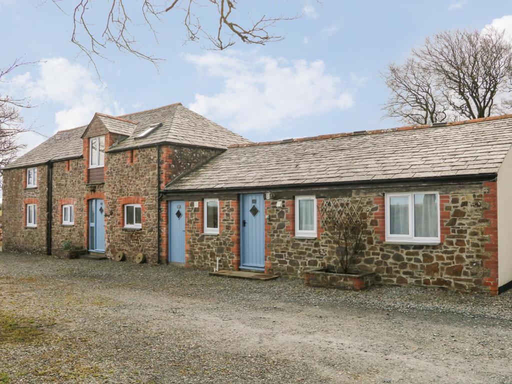 an old brick house with blue doors and windows at The Loft in Holsworthy