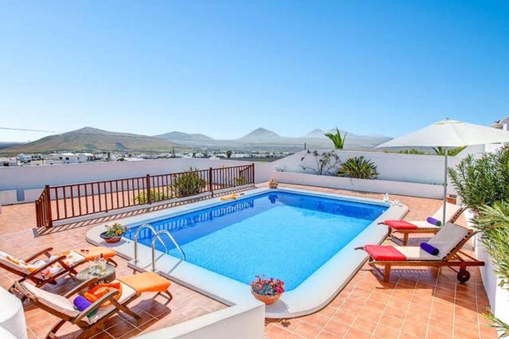a swimming pool with chairs and an umbrella at Modern Villa in Nazaret with Private Pool in Nazaret