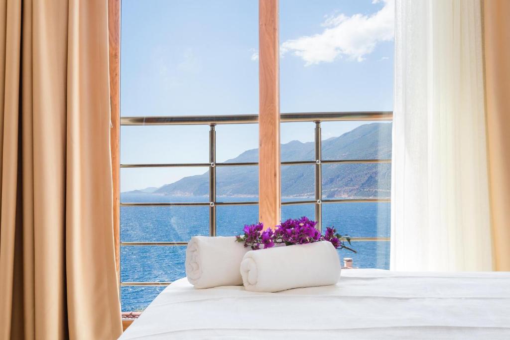a bedroom with a large window with flowers on the bed at Medimar Hotel in Kaş