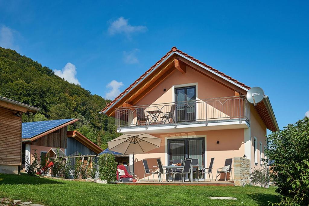 a house with a balcony with chairs and an umbrella at Ferienhof Halbig in Riedenburg