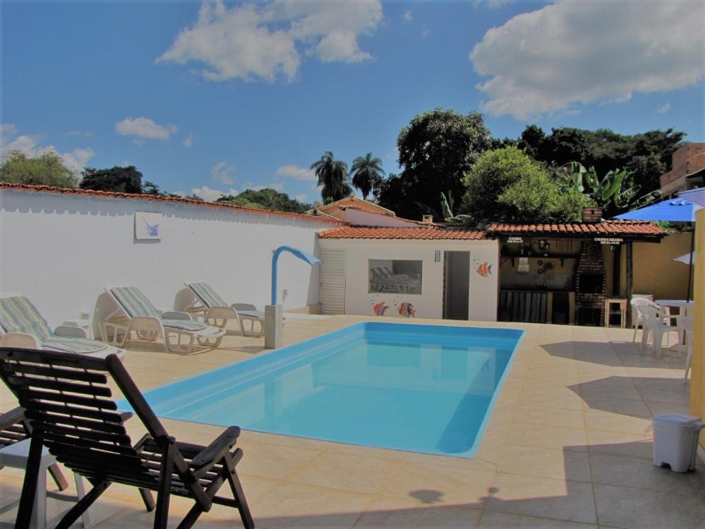 una piscina en un patio con sillas y una casa en Pousada das Bromélias, en Serra do Cipo