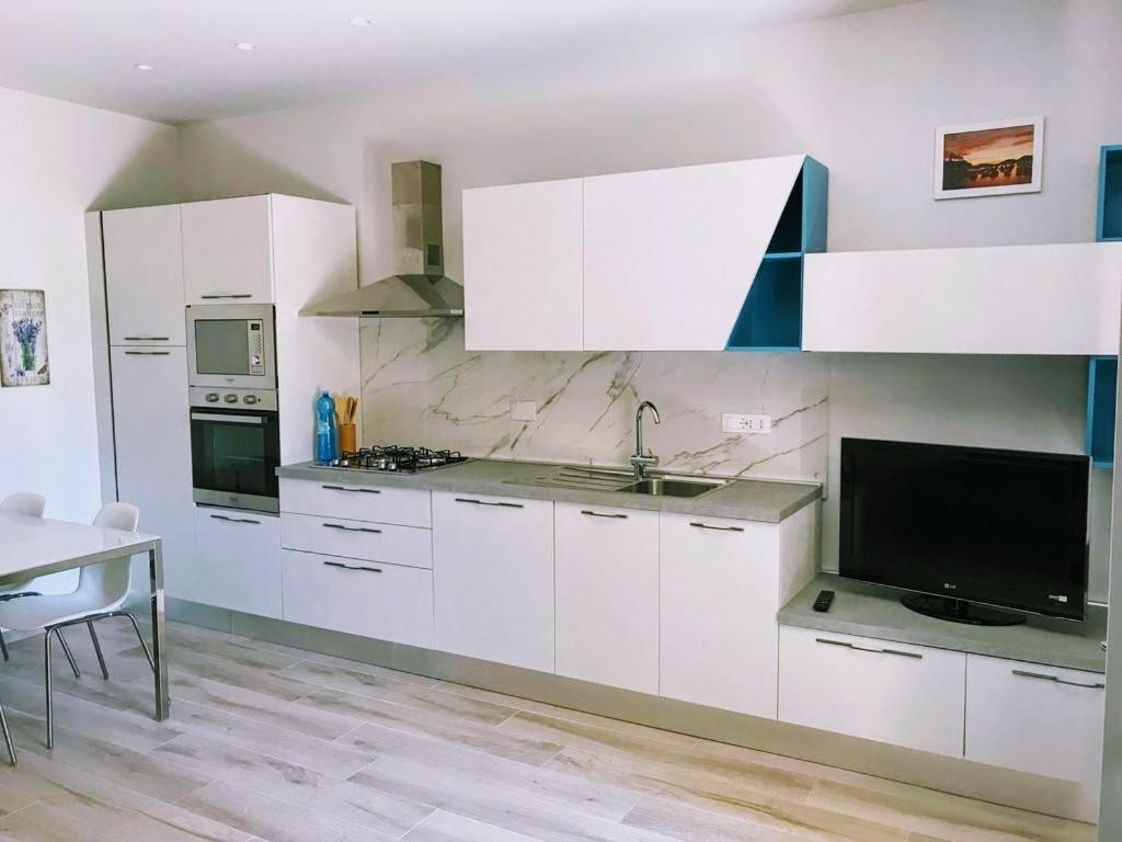 a kitchen with white cabinets and a tv and a table at Residence Mare Azzurro in Lerici