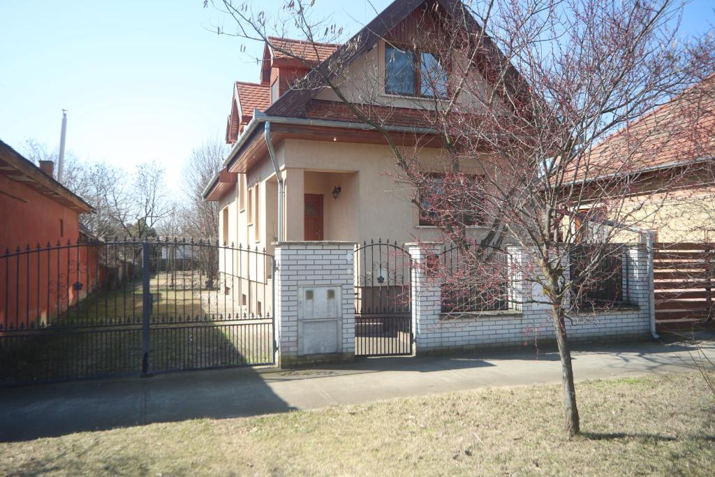 uma casa com um portão e uma árvore em frente em Ádám Vendégház Kerekegyháza em Kerekegyháza