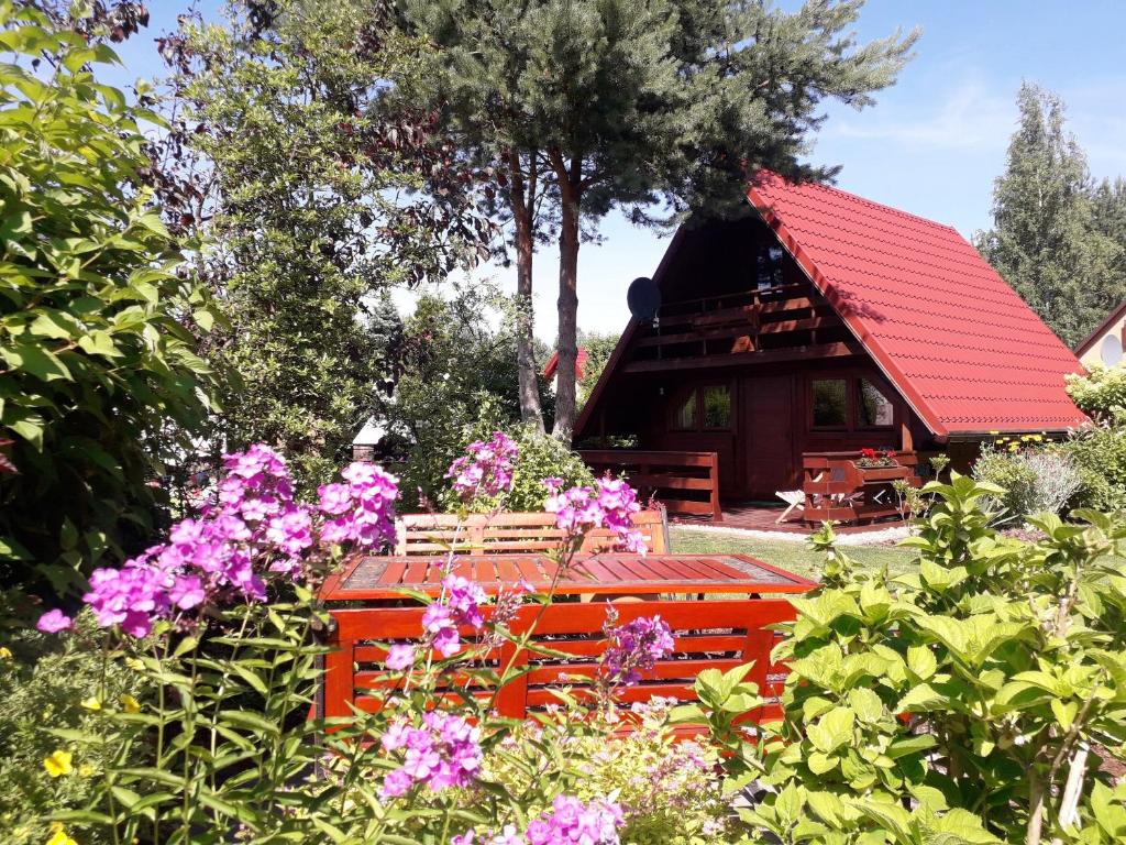 a house with a red roof and some flowers at morska chata in Lubiatowo