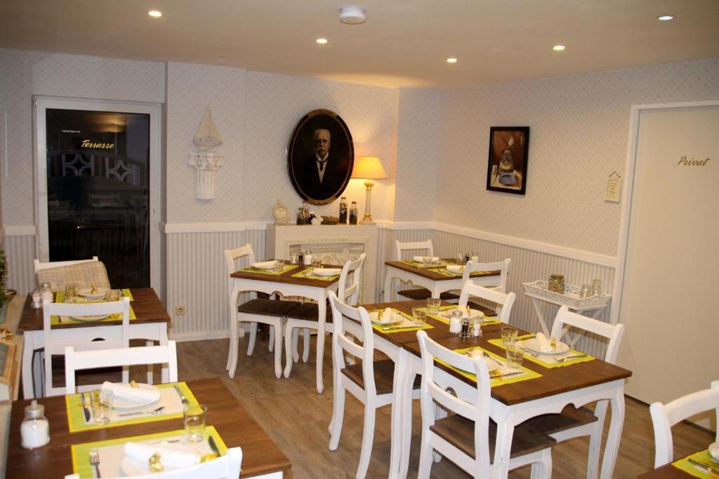 a dining room with white tables and white chairs at Pension Zur Brandung in Büsum