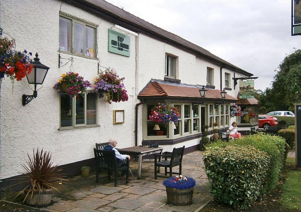 a man sitting at a table outside of a house at Casa Mere Manchester; Sure Hotel Collection by Best Western in Knutsford