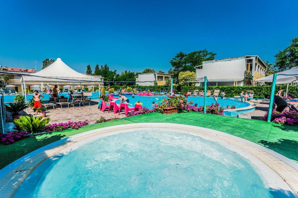 una gran piscina con personas sentadas en sillas en un complejo en Blu Marlin Residence con piscina, en Lido Adriano