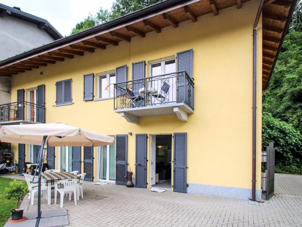 żółty dom z balkonem i parasolem w obiekcie Holiday Home Carmen by Interhome w mieście Brissago Valtravaglia