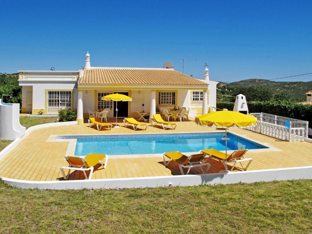 a house with a swimming pool with yellow chairs and umbrellas at Holiday Home Da Bela Vista - PAD110 by Interhome in Paderne