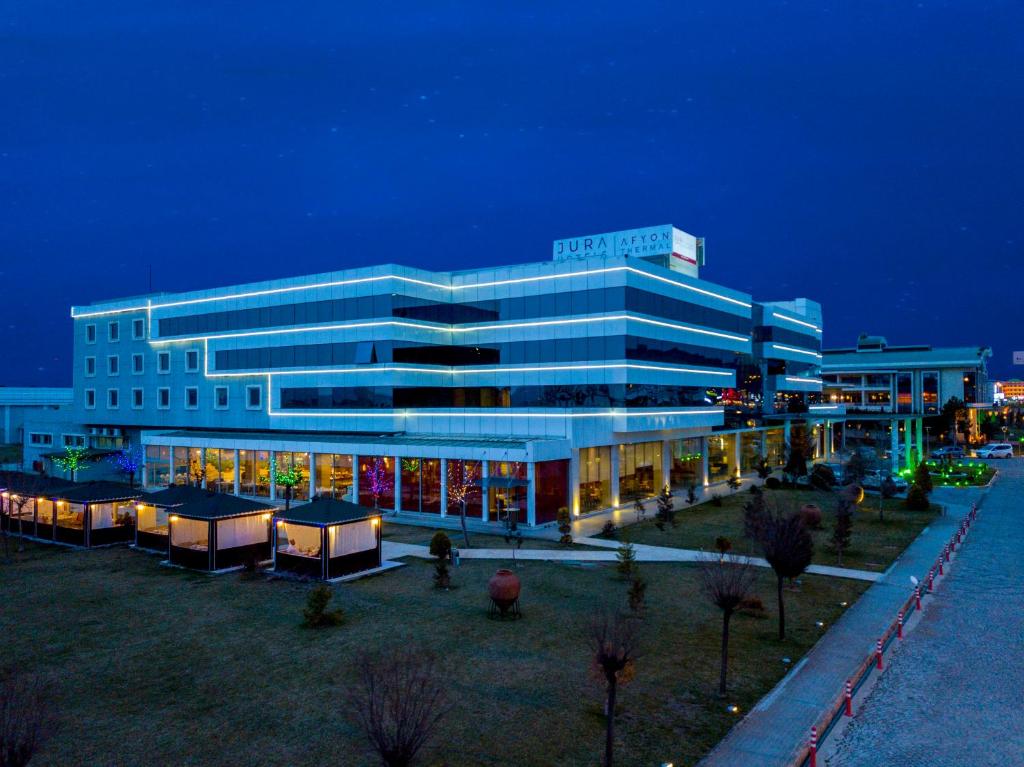 - un grand bâtiment blanc avec des lumières devant dans l'établissement Jura Hotels Afyon Thermal, à Afyon