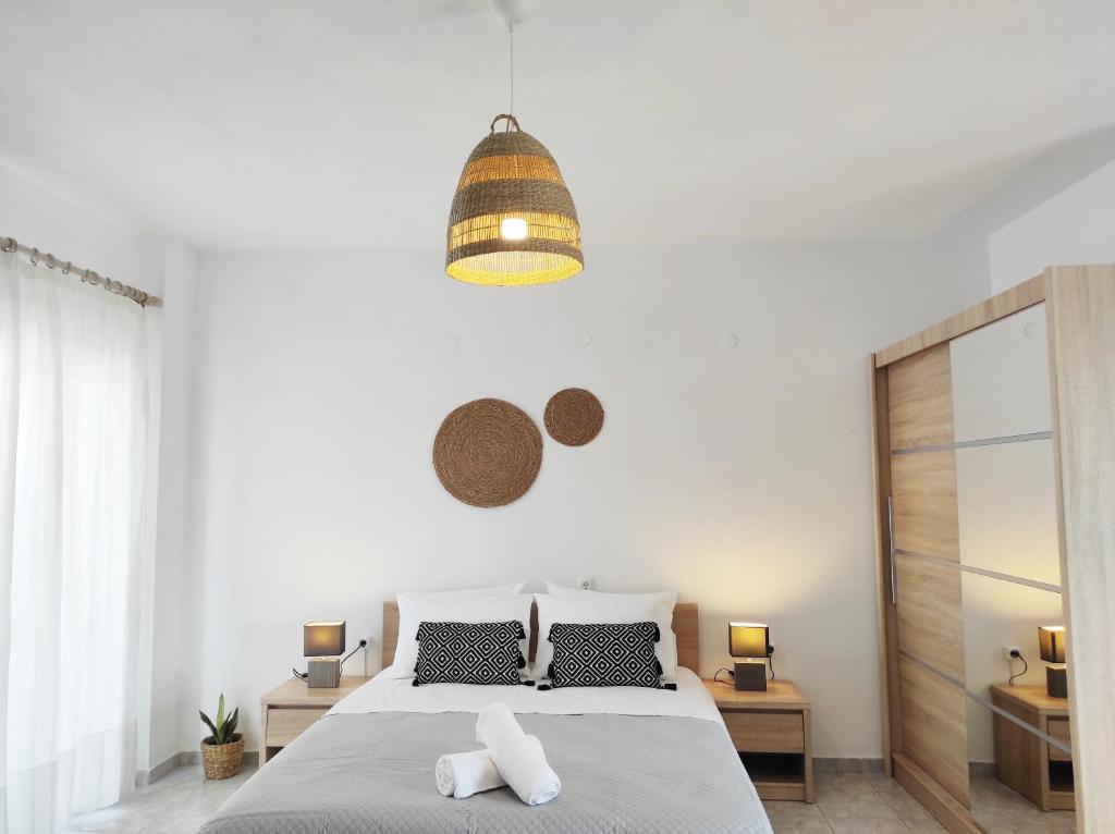 a white bedroom with a bed and a pendant light at Boheme Studios 1 in Skiathos