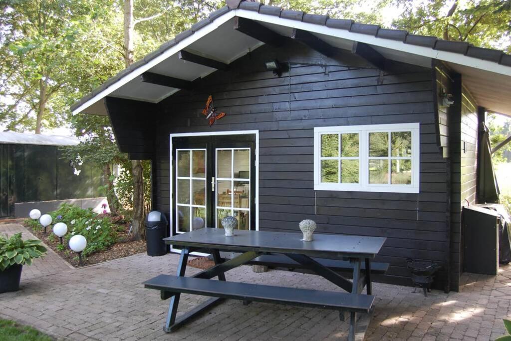 een picknicktafel voor een zwart tiny house bij Blokhut De Vlinder gelegen nabij het Pieterpad in Coevorden