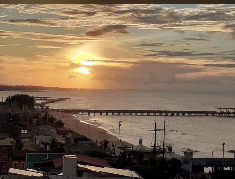 um pôr-do-sol sobre uma praia com um cais e o oceano em 501 Lindo Flat mobiliado com VISTA TOTAL MAR na Praia de Iracema em Fortaleza