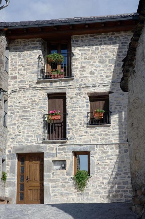 um edifício de pedra com três janelas com caixas de flores em Apartamento El Tejado em Torla