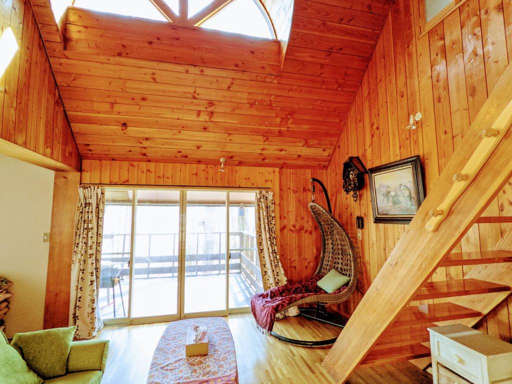 uma sala de estar com tecto de madeira e escadas em Asuka's House 八ヶ岳 em Hokuto
