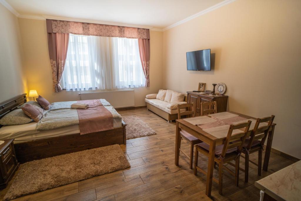 a bedroom with a bed and a table and a couch at Toscana Apartman in Gyula