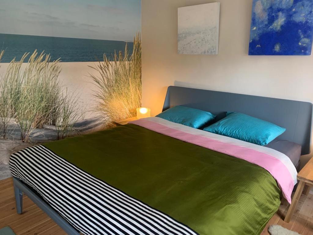 Schlafzimmer mit einem Bett mit grünen und blauen Kissen in der Unterkunft B&B De Vlasboerderij in Zonnemaire