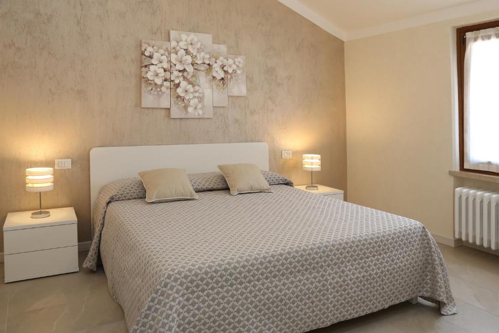 a bedroom with a bed with two night stands and two lamps at Flower Apartments in Bardolino