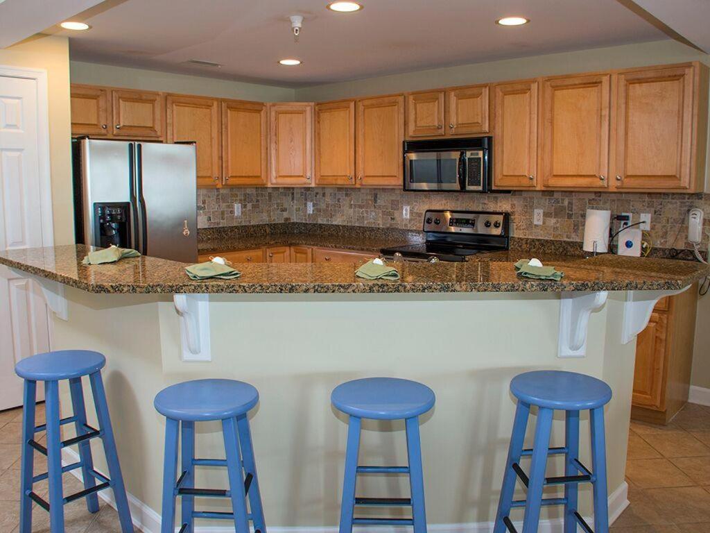 a kitchen with three blue stools at a counter at Bahia Vista I in Ocean City